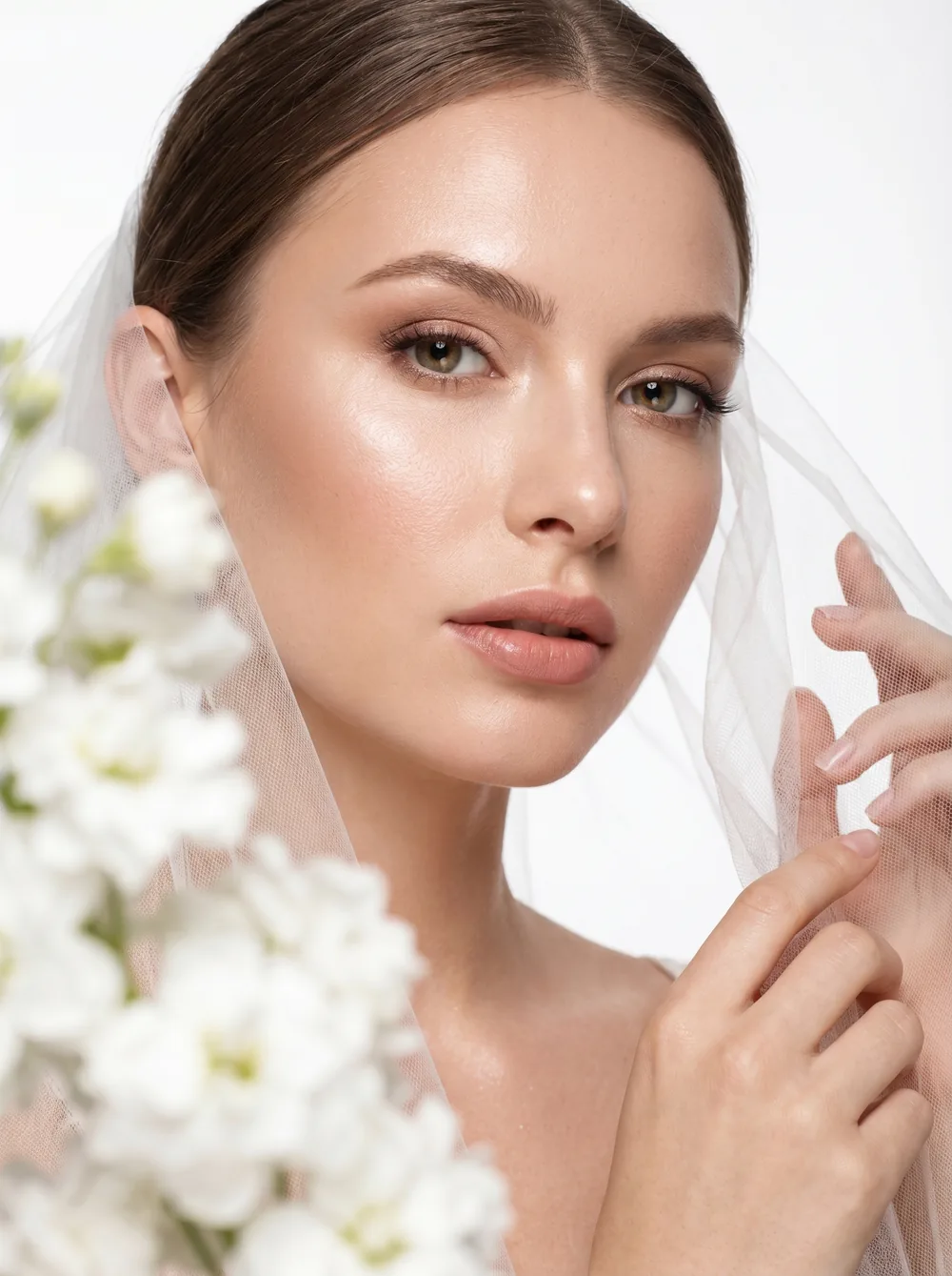 Caucasian bride with soft luminous bridal glam, veil and white florals